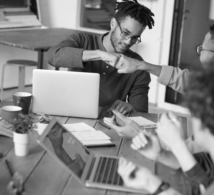 Men fist bumping over a laptop