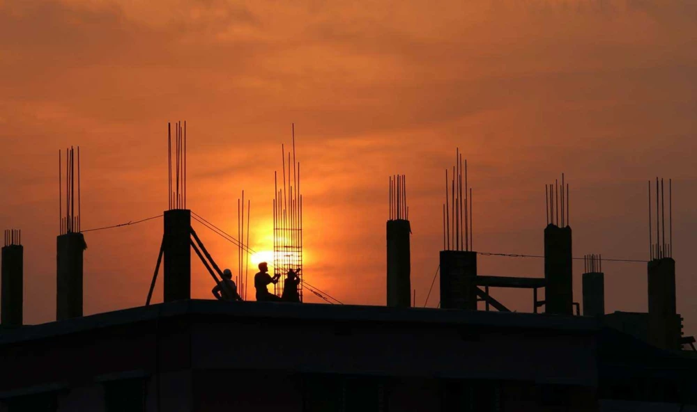 Construction workers on a building frame at sunset