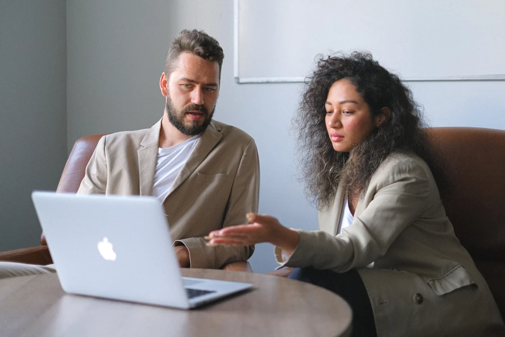 Two colleagues discussing something on a laptop screen