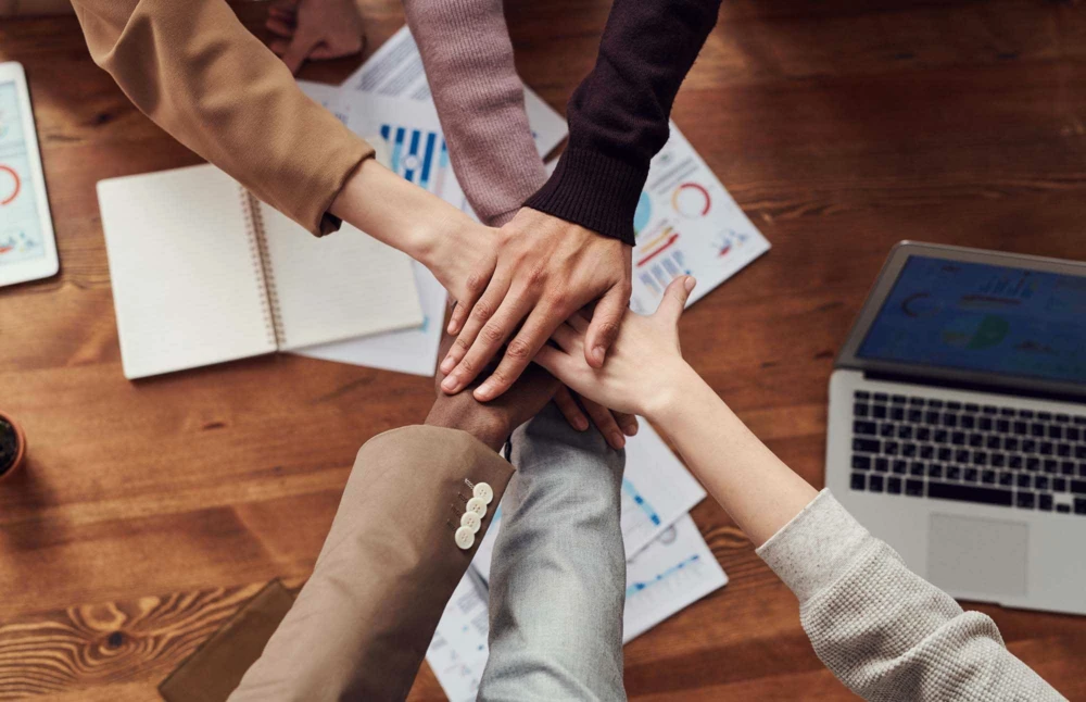 Six people place their hands together to show unity