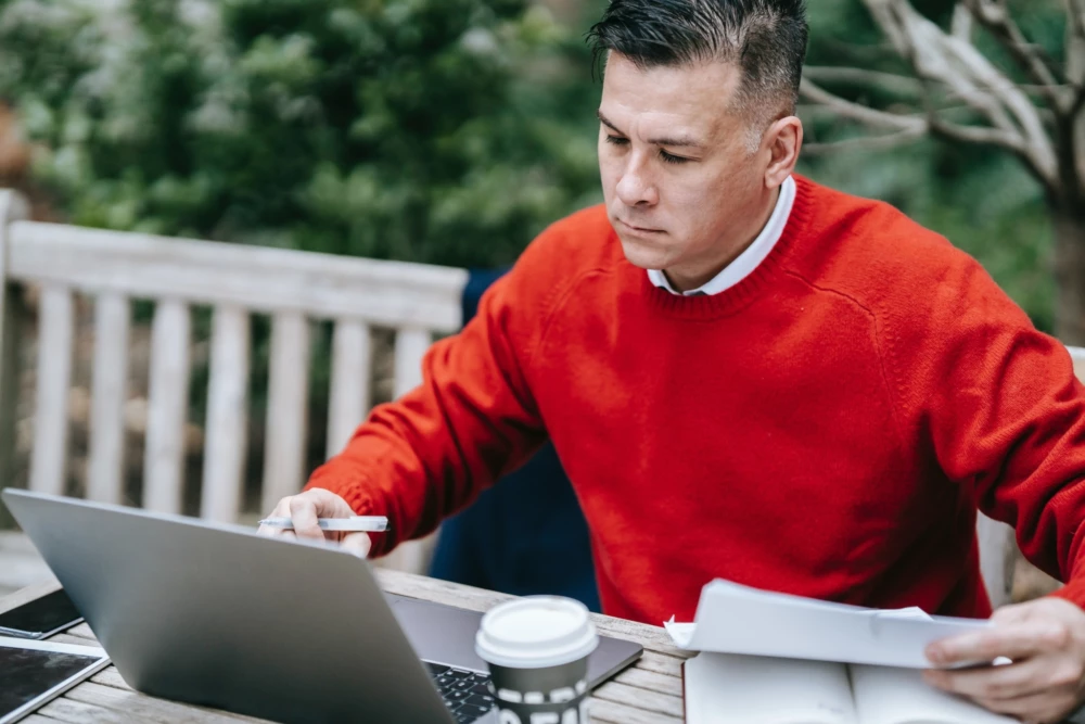 Person in an orange sweater working on a laptop