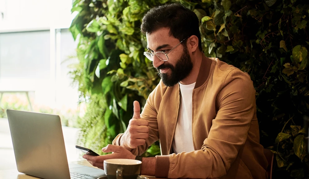 A bearded man in glasses working on the laptop
