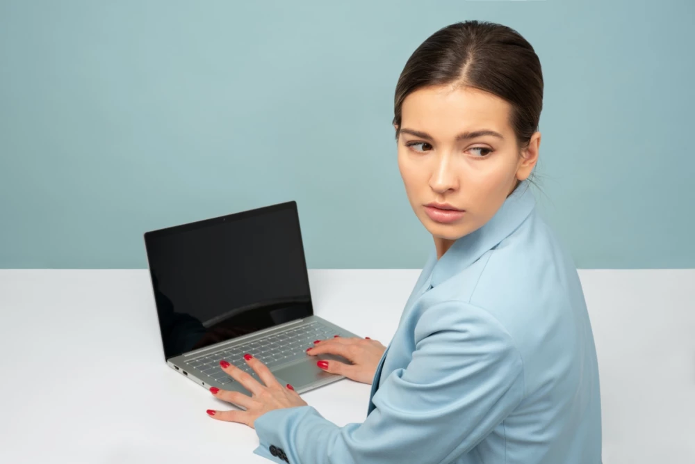 Woman on laptop looking behind her