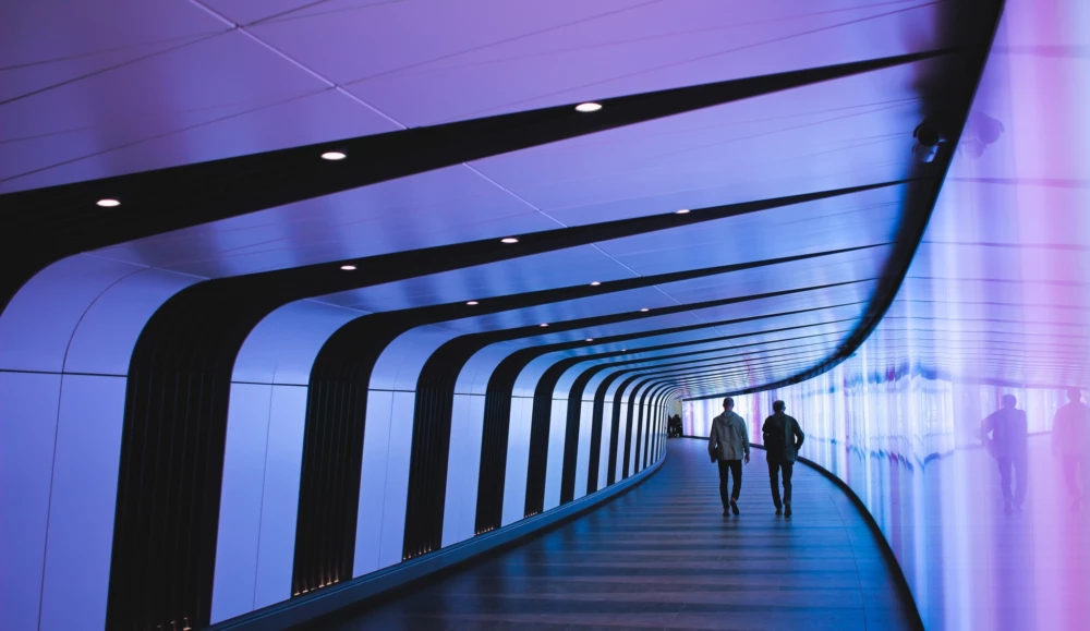 People walking down purple lit hallway